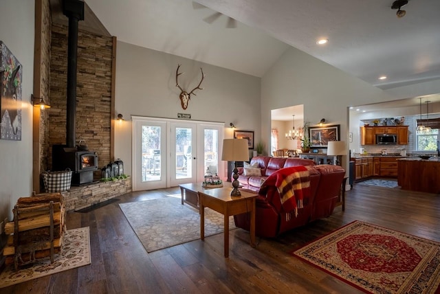 living room with a wood stove, a chandelier, high vaulted ceiling, and dark wood-type flooring