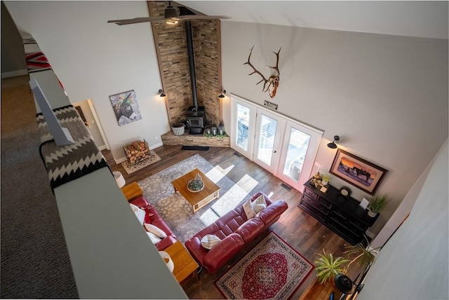 living room featuring hardwood / wood-style floors, a wood stove, high vaulted ceiling, and french doors