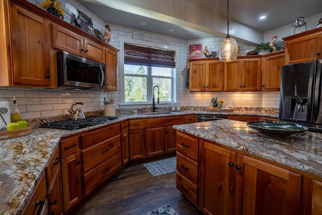 kitchen with sink, stainless steel appliances, tasteful backsplash, light stone counters, and dark hardwood / wood-style flooring