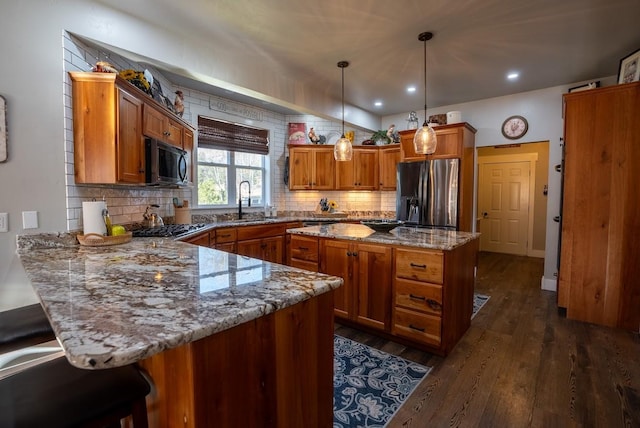 kitchen featuring light stone countertops, dark wood-type flooring, stainless steel refrigerator with ice dispenser, decorative light fixtures, and a kitchen bar