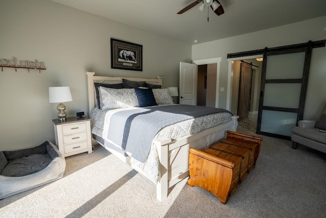 bedroom with ceiling fan, a barn door, and light colored carpet