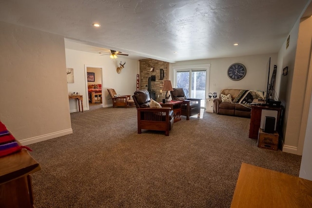 living room featuring a wood stove, ceiling fan, dark carpet, and a textured ceiling