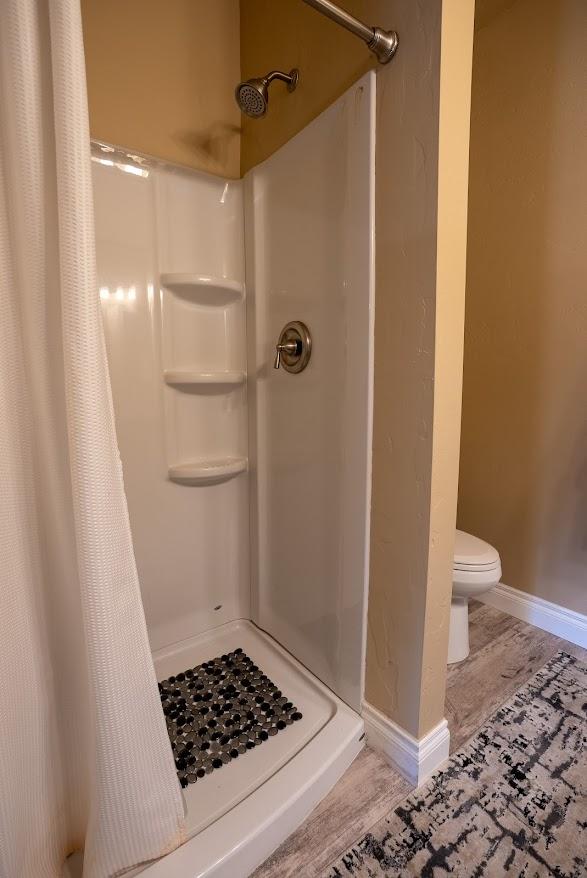 bathroom with a shower with shower curtain, toilet, and hardwood / wood-style floors