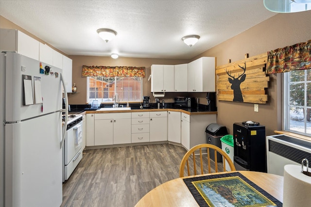 kitchen featuring white cabinets, a textured ceiling, white appliances, and a wealth of natural light