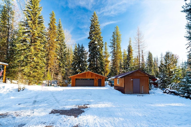 yard layered in snow featuring a garage and a storage unit