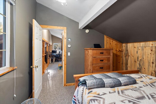 bedroom featuring wooden walls and vaulted ceiling