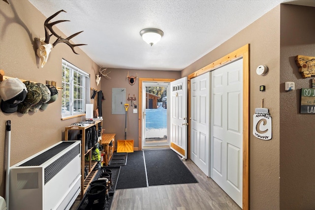 foyer entrance featuring electric panel, hardwood / wood-style floors, heating unit, and a textured ceiling