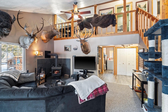 living room with hardwood / wood-style flooring, ceiling fan, a wood stove, and a textured ceiling