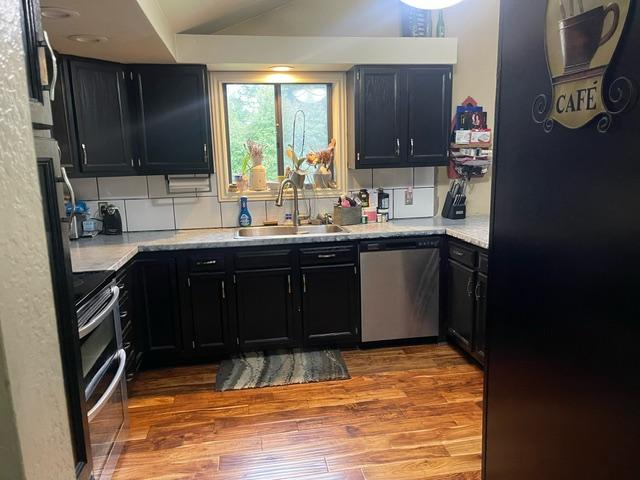 kitchen featuring lofted ceiling, stainless steel appliances, sink, and wood-type flooring