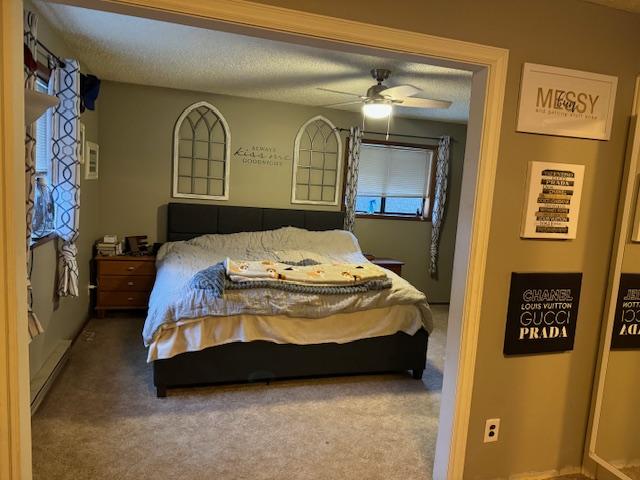 bedroom with ceiling fan, carpet floors, and a textured ceiling