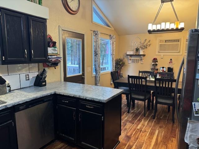 kitchen featuring appliances with stainless steel finishes, pendant lighting, lofted ceiling, kitchen peninsula, and dark wood-type flooring