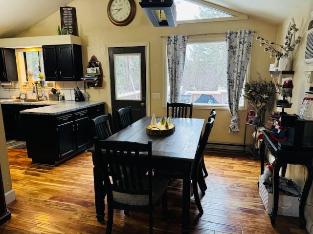 dining space featuring sink, vaulted ceiling, and light hardwood / wood-style floors