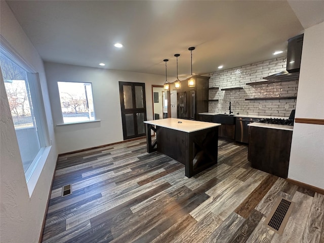 kitchen with stainless steel appliances, a kitchen island, tasteful backsplash, and dark wood-type flooring