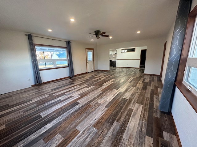 unfurnished living room featuring ceiling fan and dark wood-type flooring