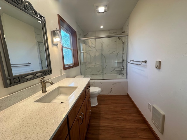 full bathroom featuring hardwood / wood-style flooring, vanity, toilet, and tiled shower / bath