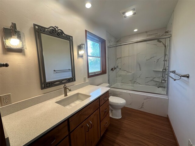 full bathroom featuring toilet, hardwood / wood-style floors, vanity, and tiled shower / bath combo