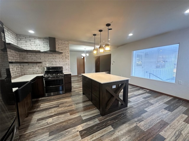 kitchen with dark hardwood / wood-style flooring, wall chimney exhaust hood, decorative light fixtures, stainless steel stove, and a kitchen island