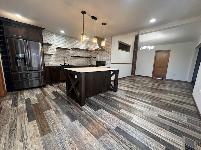 kitchen with stainless steel fridge with ice dispenser, a center island, dark hardwood / wood-style floors, hanging light fixtures, and a breakfast bar area