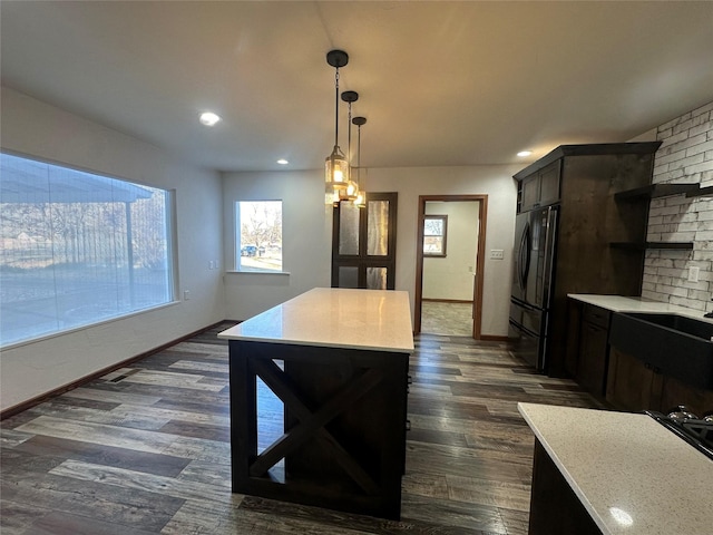 kitchen featuring pendant lighting, dark wood-type flooring, fridge, dark brown cabinetry, and a chandelier