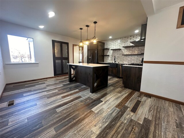 kitchen featuring hanging light fixtures, stainless steel appliances, dark hardwood / wood-style floors, decorative backsplash, and a kitchen island