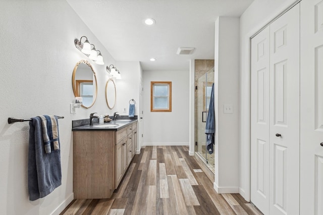 bathroom with a shower with door, vanity, and wood-type flooring