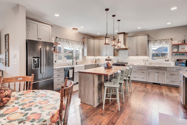 kitchen with dark hardwood / wood-style flooring, appliances with stainless steel finishes, pendant lighting, a kitchen island, and custom exhaust hood