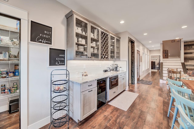 kitchen featuring light stone countertops, tasteful backsplash, wine cooler, dark hardwood / wood-style flooring, and oven