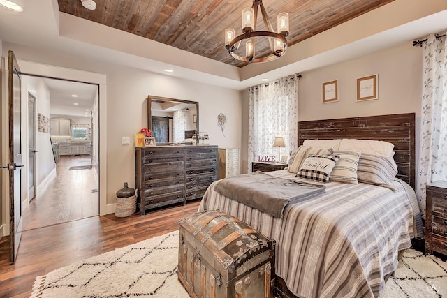 bedroom featuring a tray ceiling, wooden ceiling, hardwood / wood-style floors, and a chandelier