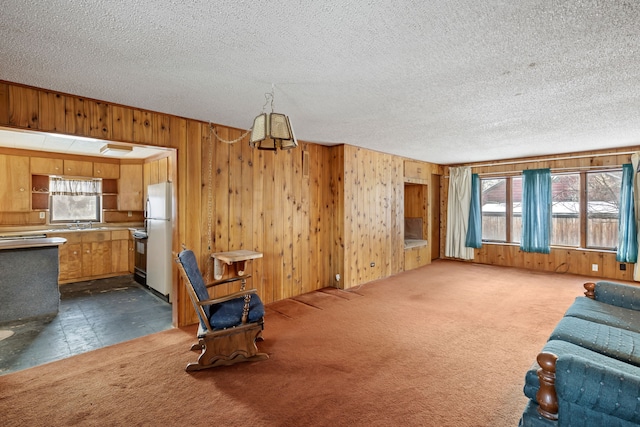 living room with a textured ceiling, dark carpet, and wood walls