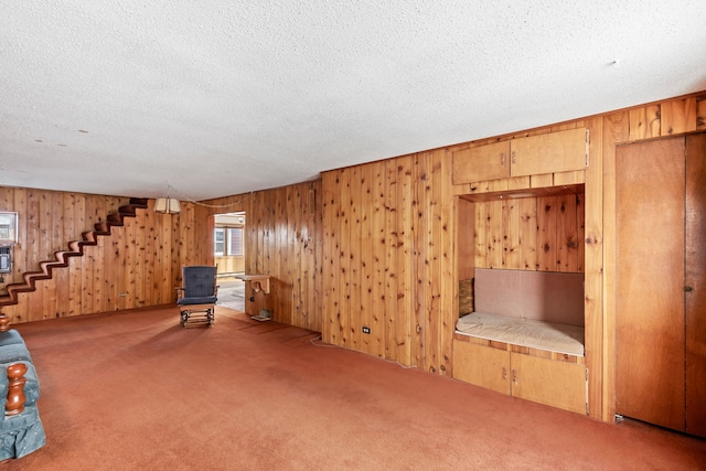 interior space with carpet flooring, wooden walls, and a textured ceiling