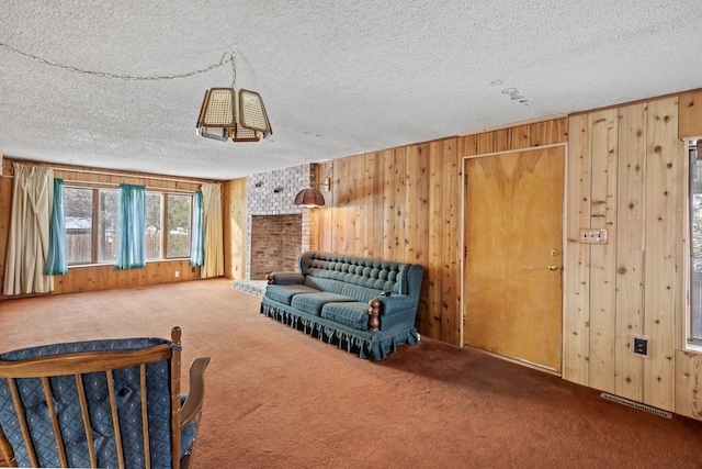 living room with carpet, a textured ceiling, and wood walls