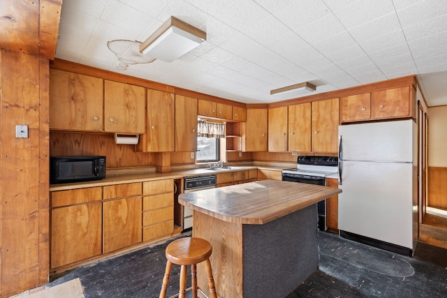 kitchen featuring wood walls, a kitchen island, white appliances, and sink