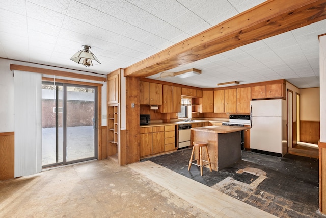 kitchen featuring a kitchen breakfast bar, white appliances, a kitchen island, and wooden walls