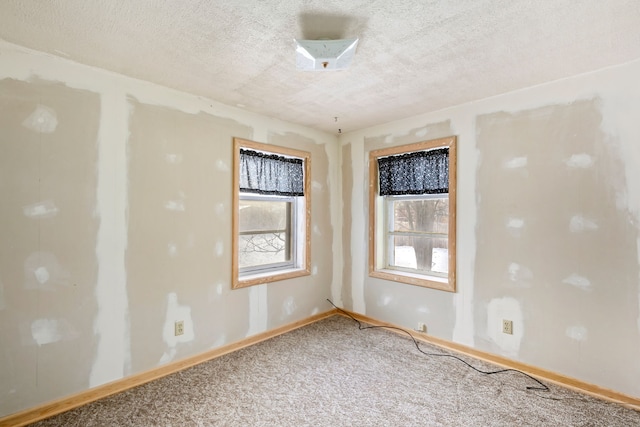 unfurnished room featuring carpet flooring, a textured ceiling, and plenty of natural light