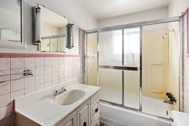 bathroom featuring vanity, enclosed tub / shower combo, and tile walls