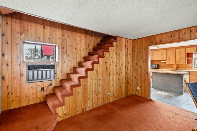 stairway featuring wood walls, carpet floors, and a textured ceiling