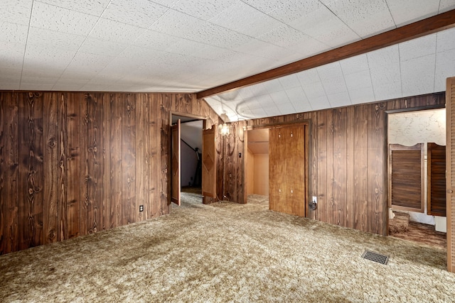 unfurnished room with carpet flooring, vaulted ceiling with beams, and wood walls