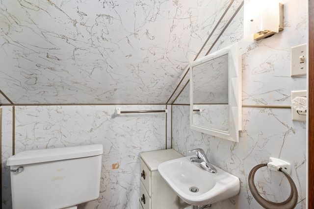 bathroom with toilet, sink, and tile walls