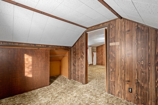 additional living space featuring wooden walls, carpet floors, and vaulted ceiling