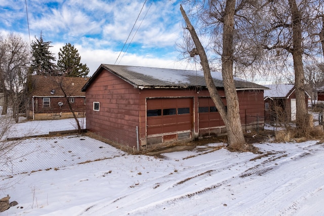 view of snow covered exterior featuring a garage and an outdoor structure