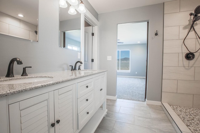 bathroom with tiled shower and vanity