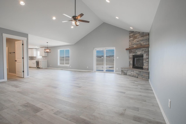 unfurnished living room featuring high vaulted ceiling, a fireplace, ceiling fan, and light wood-type flooring