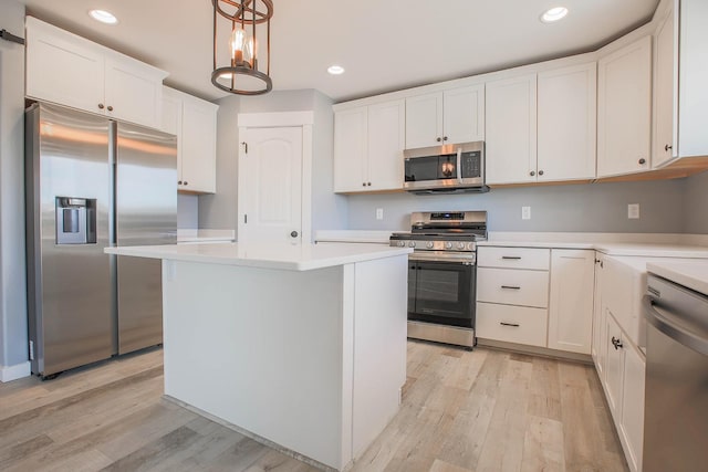 kitchen with pendant lighting, a center island, stainless steel appliances, light wood-type flooring, and white cabinetry