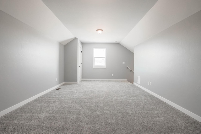 additional living space featuring vaulted ceiling and carpet floors