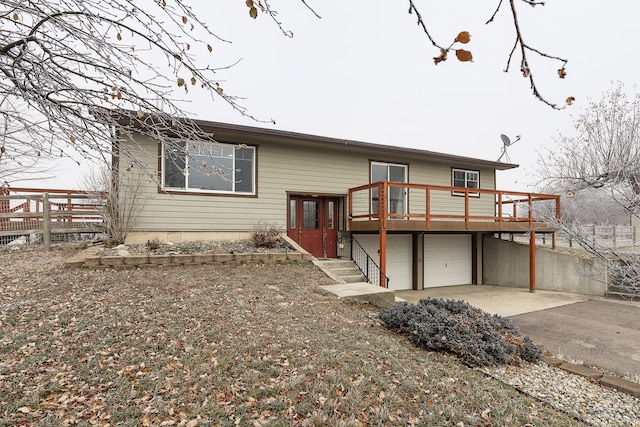 rear view of house featuring a garage and a wooden deck