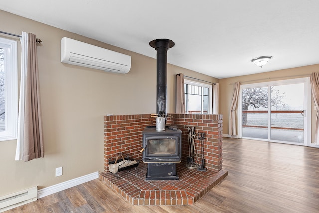 details with hardwood / wood-style floors, a wood stove, baseboard heating, and a wall unit AC