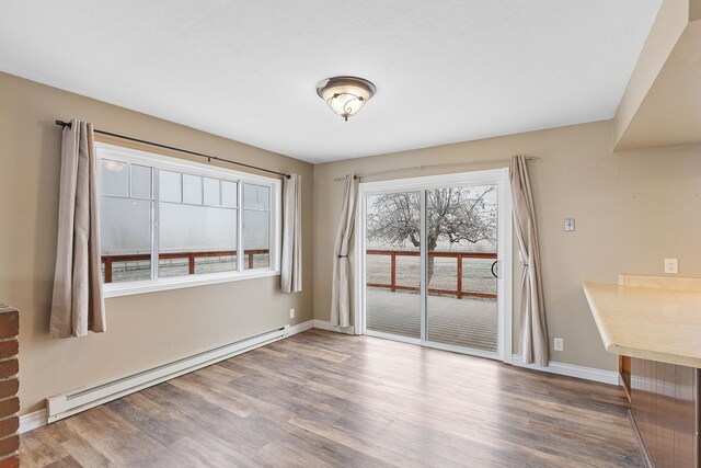 unfurnished dining area featuring hardwood / wood-style flooring and baseboard heating