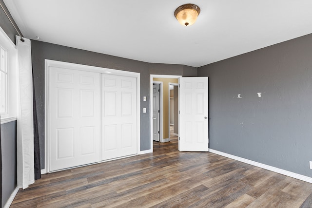 unfurnished bedroom with dark hardwood / wood-style flooring and a closet