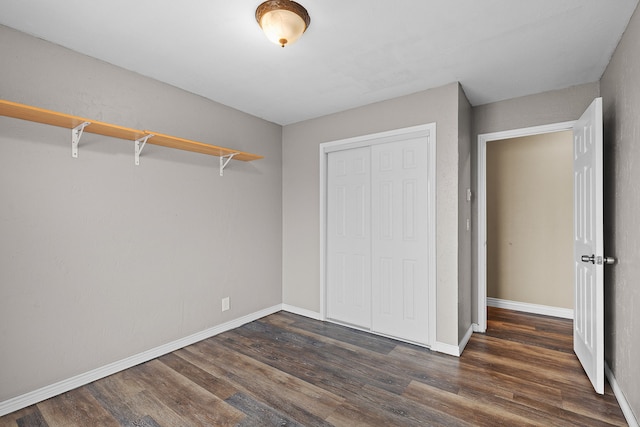 unfurnished bedroom featuring a closet and dark wood-type flooring