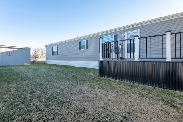 back of house with a lawn and a storage shed